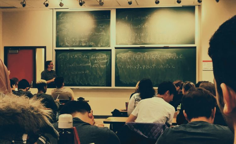 student sitting on chairs in front of chalkboard